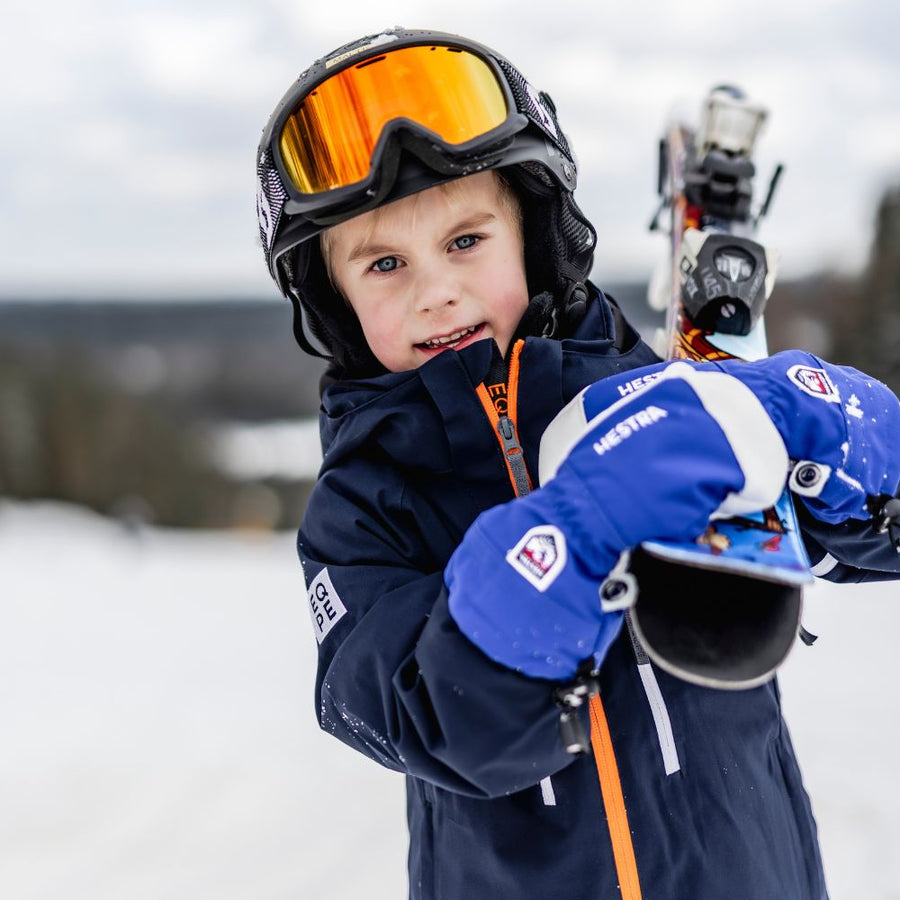 Child wearing Hestra kids ski gloves on snowy slope