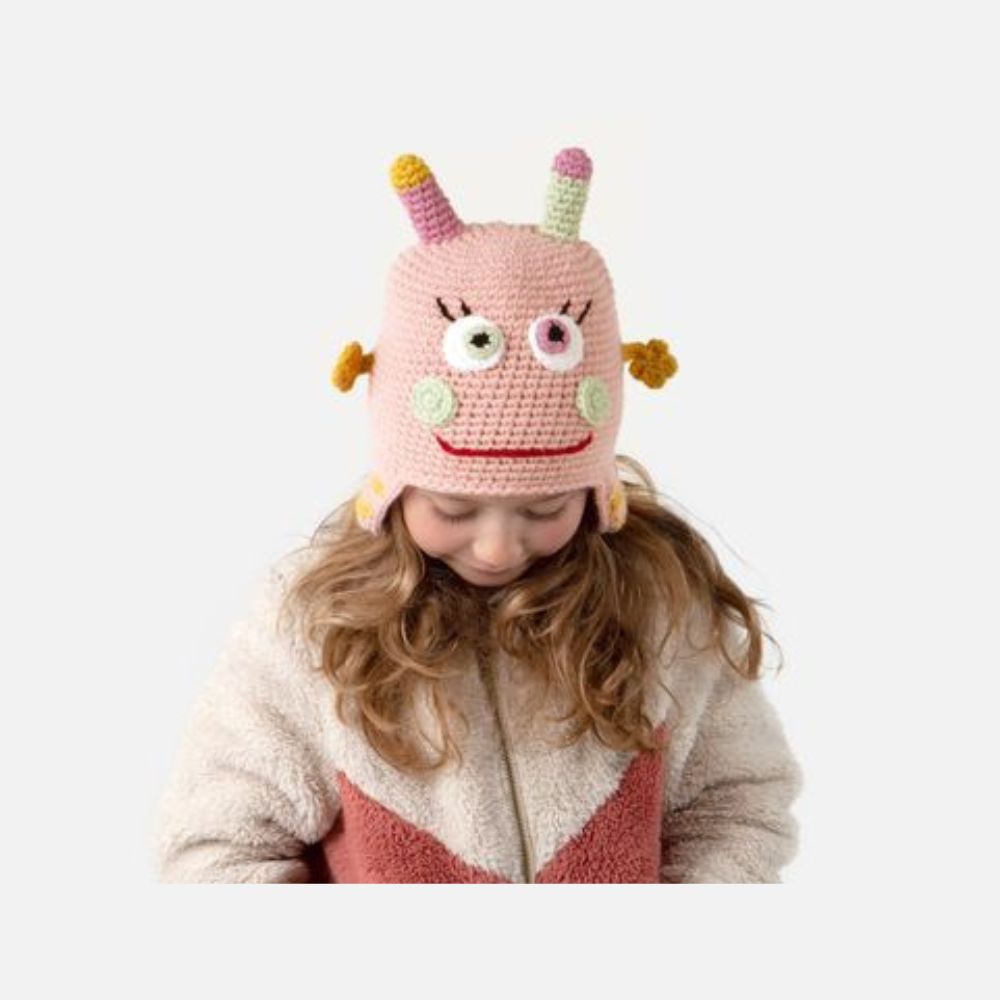 Child wearing a pink monster hat on a white background