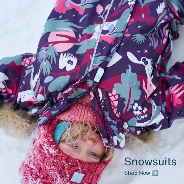 A child lying on snow wearing a colorful printed snowsuit with pink, purple, teal, and white floral and animal motifs, along with a pink knit beanie. Text in the lower right reads 'Snowsuits Shop Now'.