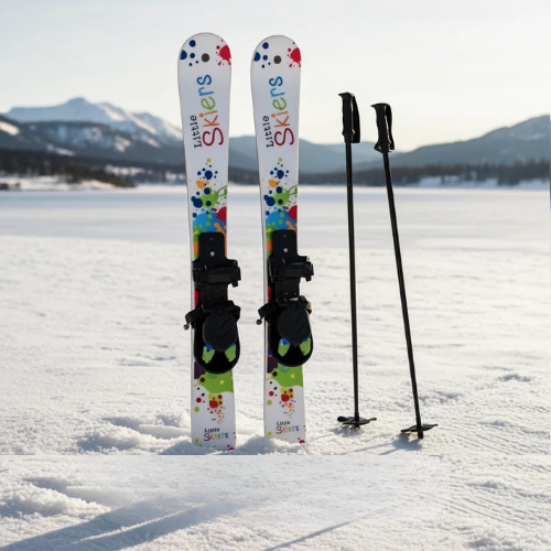 Kids skis with colorful designs and ski poles on a snowy surface with mountains in the background